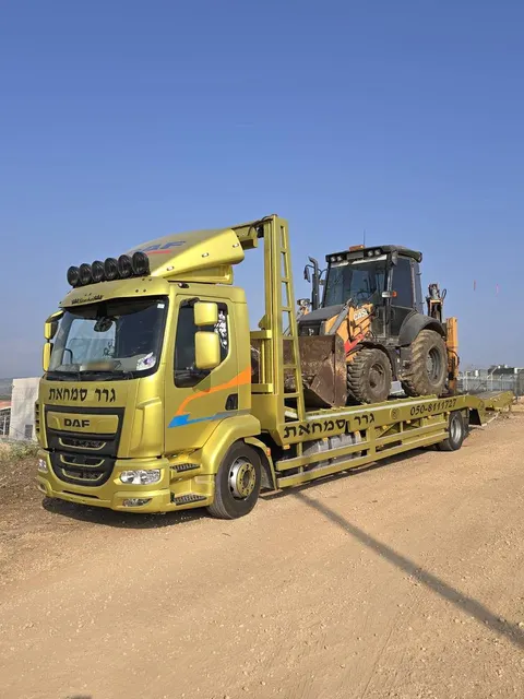 מחפרון מועמס על משאית הגרר של גרר סמחאת בשטח עפר